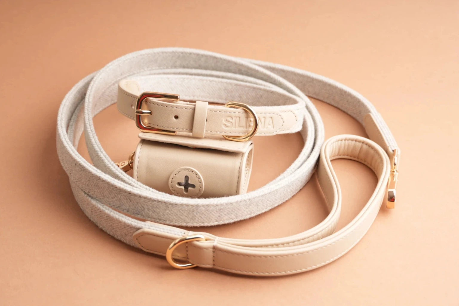 Siliena Set in Beige: Hundehalsband, Hundeleine und Kotbeutelhalter aus Echtleder und Textil auf beigem Hintergrund.