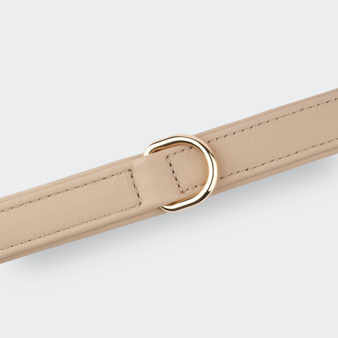 Detailaufnahme des beigen Hundehalsbands mit goldfarbenem D-Ring aus Echtleder.